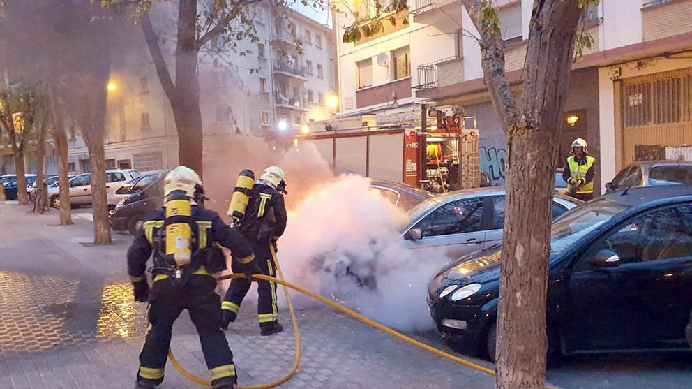 Los bomberos trabajan en la extinción de los vehículos quemados premeditadamente en Pamplona.