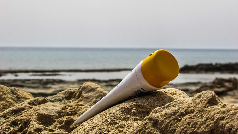 Imagen de un bote de crema solar junto a la orilla de una playa ARCHIVO