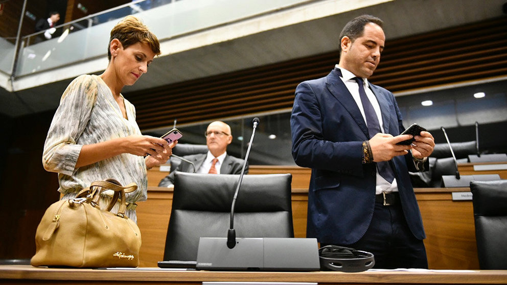 María Chivite y Ramón Alzórriz consulta sus teléfonos durante la sesión del Parlamento de Navarra. PABLO LASAOSA