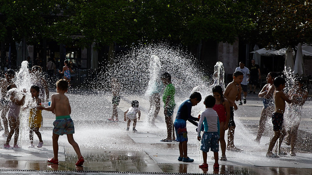 Unos niños juegan en la 'fuente de chorros' de la Plaza de Yamaguchi durante la primera ola de calor del verano en Pamplona. IÑIGO ALZUGARAY