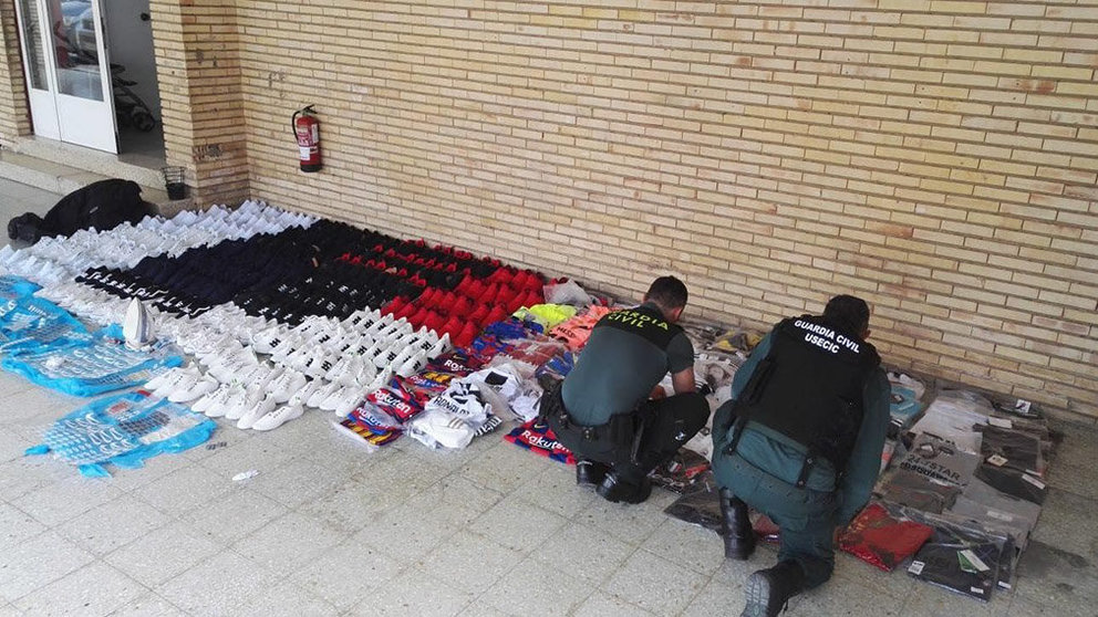 Dos agentes de la Guardia Civil con parte de la mercancia de ropa falsificada incautada. GUARDIA CIVIL