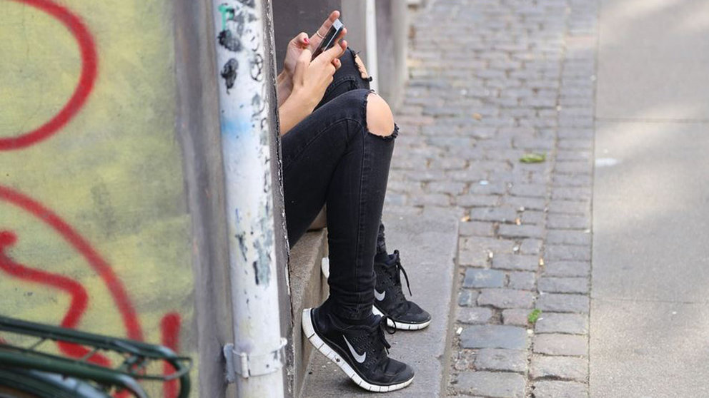 Una joven utiliza su teléfono móvil en la calle ARCHIVO