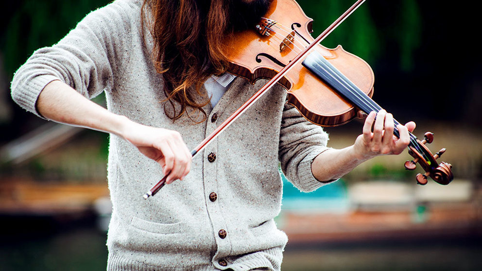 Un mujer interpreta una pieza con un violín en la calle.