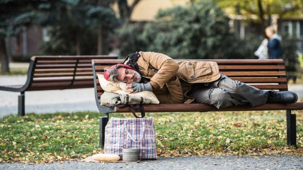 Una persona sin hogar durmiendo en un banco ARCHIVO