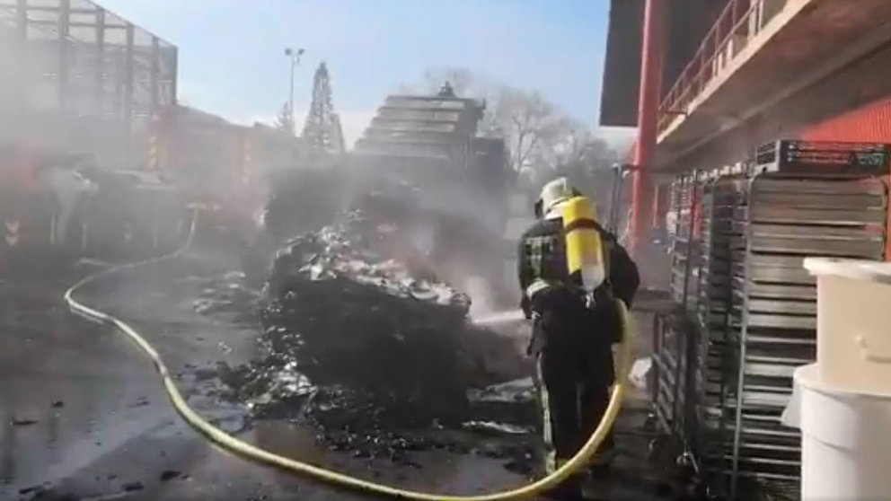 Un bombero trabaja en la extinción de un incendio en un contendor cercano a las cocinas de la Universidad de Navarra. TWITTER