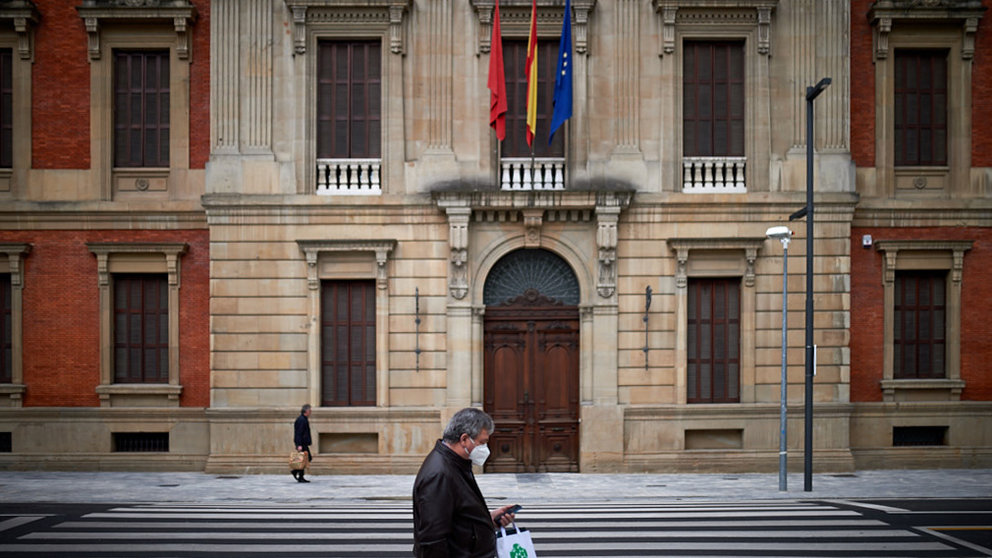 Un hombre con mascarilla pasa delante del Parlamento de Navarra durante la crisis por coronavirus en Pamplona. Miguel Osés