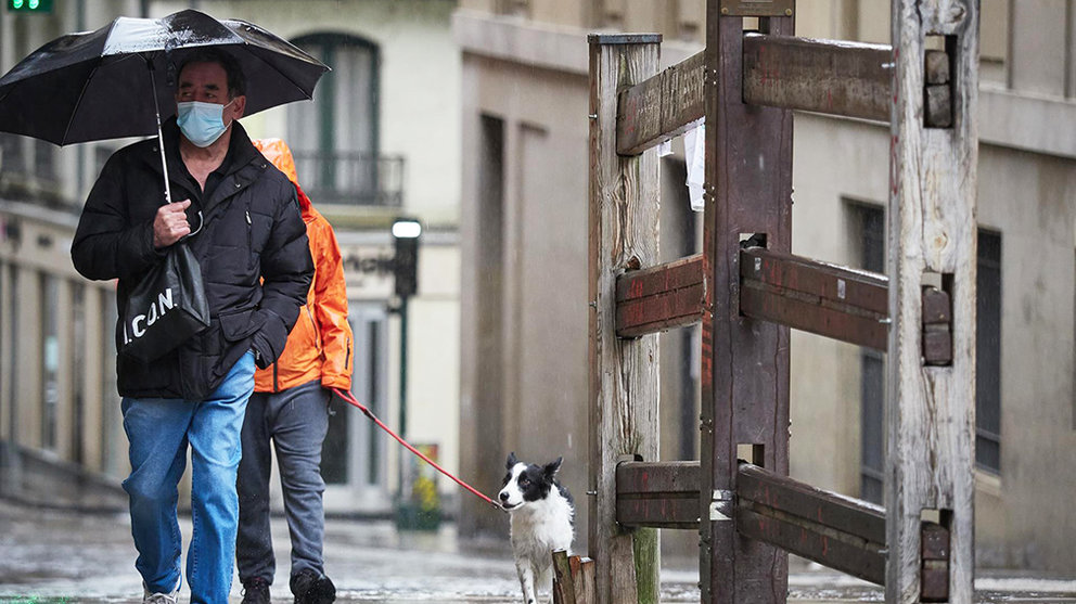 Un hombre con mascarilla camina bajo la lluvia junto al vallado permanente del encierro de Pamplona de la cuesta de Santo Domingo - Eduardo Sanz - Europa Press.