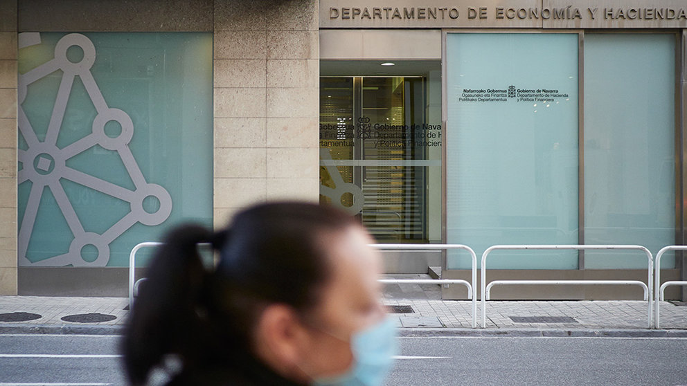 Una mujer con mascarilla pasa junto al Departamento de Economía y Hacienda un día después de que el Gobierno anunciara las medidas de desescalada por la pandemia del coronavirus, en Pamplona. ARCHIVO