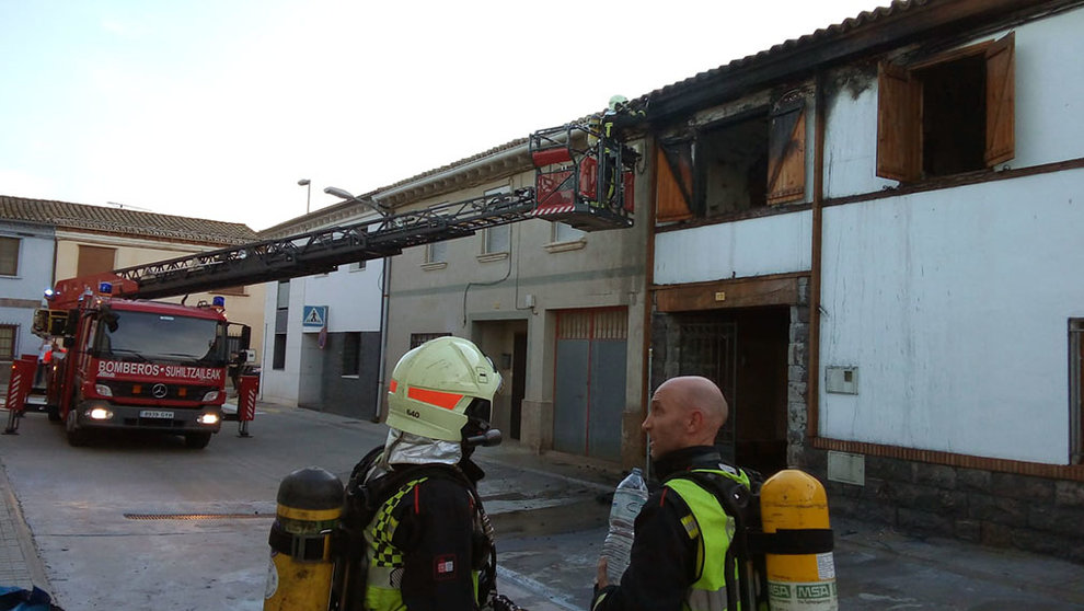 Dos bomberos junto a la vivienda que ha sufrido un grave incendio en Buñuel. CEDIDA.