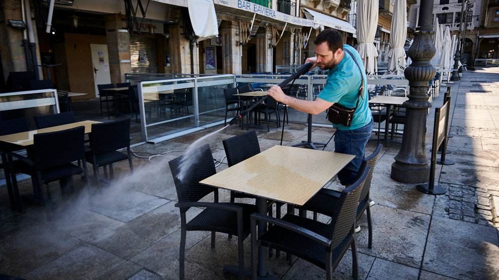 Una persona limpia y desinfecta un bar en la Plaza del Castillo de Pamplona durante la preparación de la fase 1, que implica la apertura de terrazas. PABLO LASAOSA