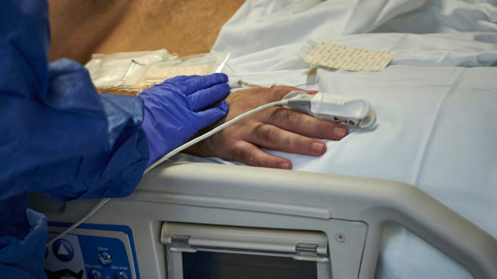 Una enfermera le coge la mano a un paciente de la UCI. PABLO LASAOSA