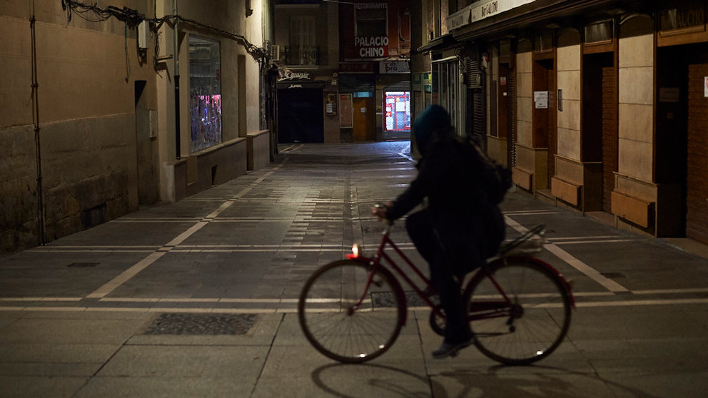 Una mujer circula en bici por el Casco Viejo de Pamplona minutos antes del comienzo del toque de queda. PABLO LASAOSA