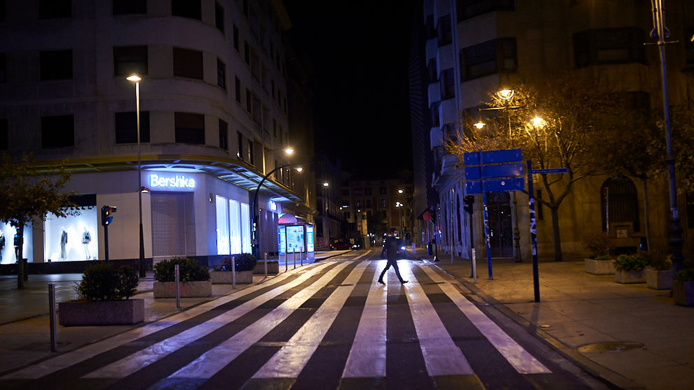 Una persona cruza un paso de cebra en el centro de Pamplona minutos antes del comienzo del toque de queda. PABLO LASAOSA