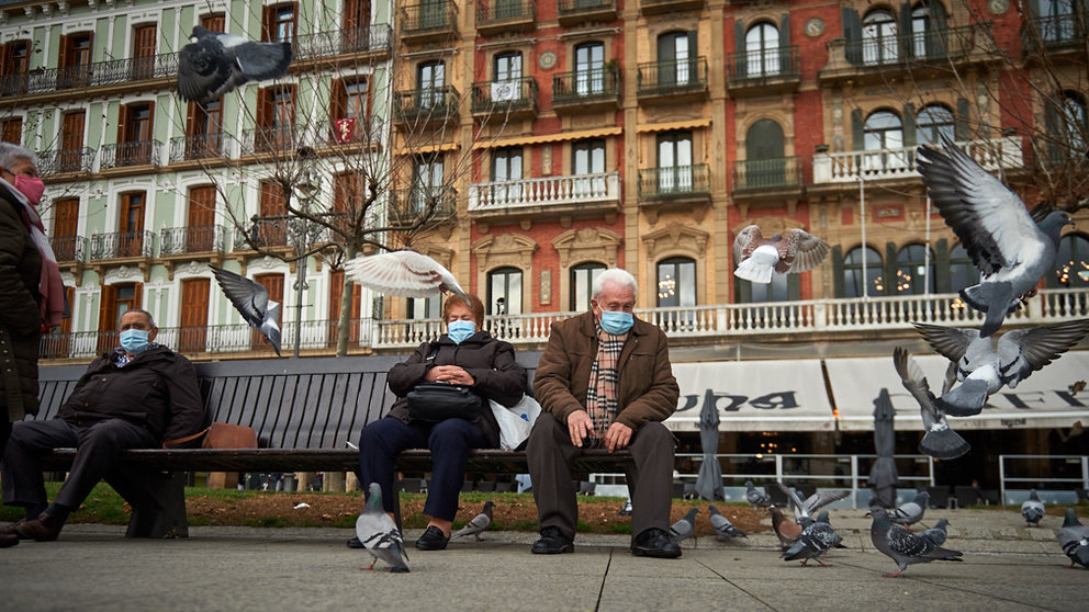 Dos personas dan de comer a las palomas en la Plaza del Castillo de Pamplona durante la pandemia de coronavirus. MIGUEL OSÉS