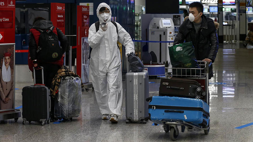 Dos pasajeros caminan por el aeropuerto de Fiumicino, en Roma, con trajes y mascarillas para protegerse del coronavirus. Cecilia Fabiano/LaPresse/DPA