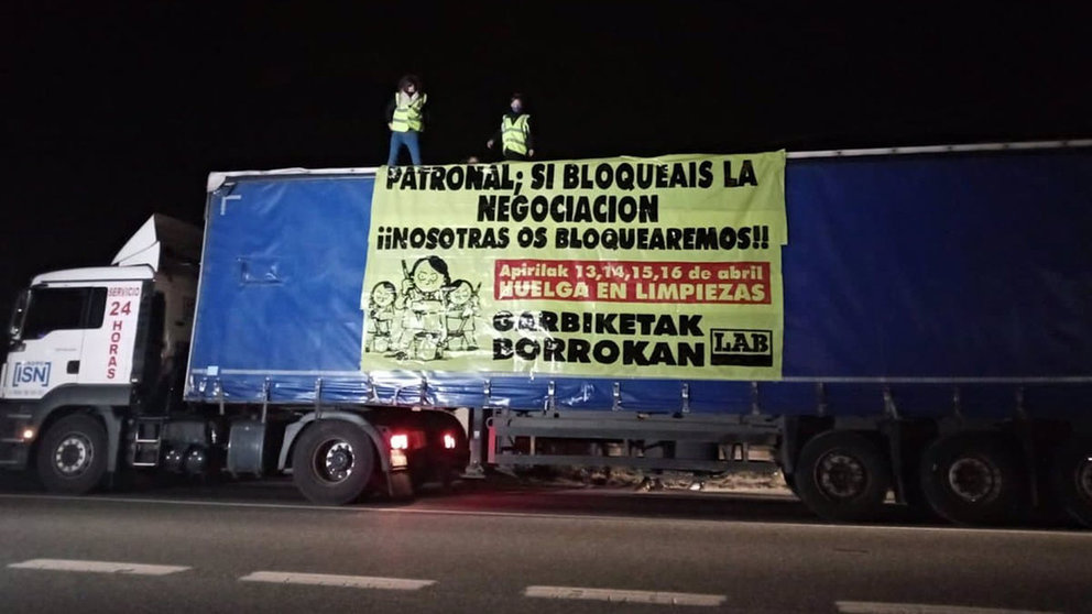 Dos trabajadoras del sector de limpiezas sobre un camión de ISN despliegan una pancarta en contra del bloqueo de la negociación del convenio sectorial. LAB