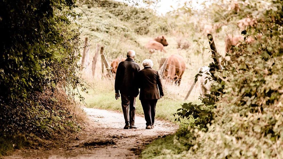 Dos personas mayores caminan por un camino rural. ARCHIVO