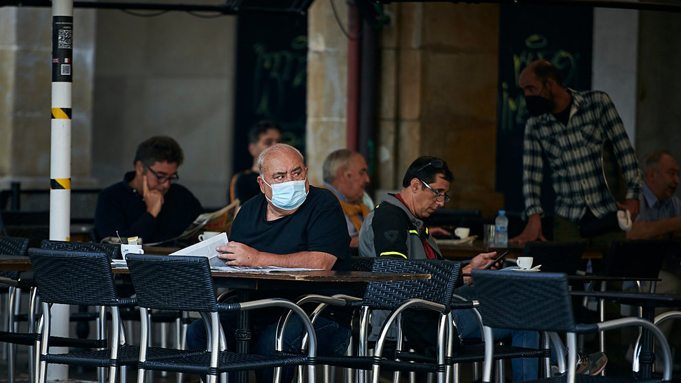 Un hombre con mascarilla se toma algo en una terraza de un bar de la Plaza del Castillo de Pamplona. PABLO LASAOSA