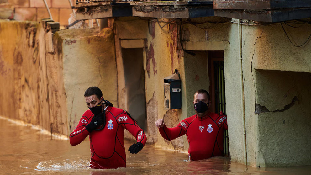 Trabajadores de Protección Civil caminan por una calle inundada, a 12 de diciembre de 2021, en Tudela. Iván Delgado (Europa Press)