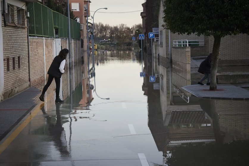 Archivo - Una persona del vecindario cruza una de las calles inundadas, a 12 de diciembre de 2021, en San Adrián. Eduardo Sanz - Europa Press