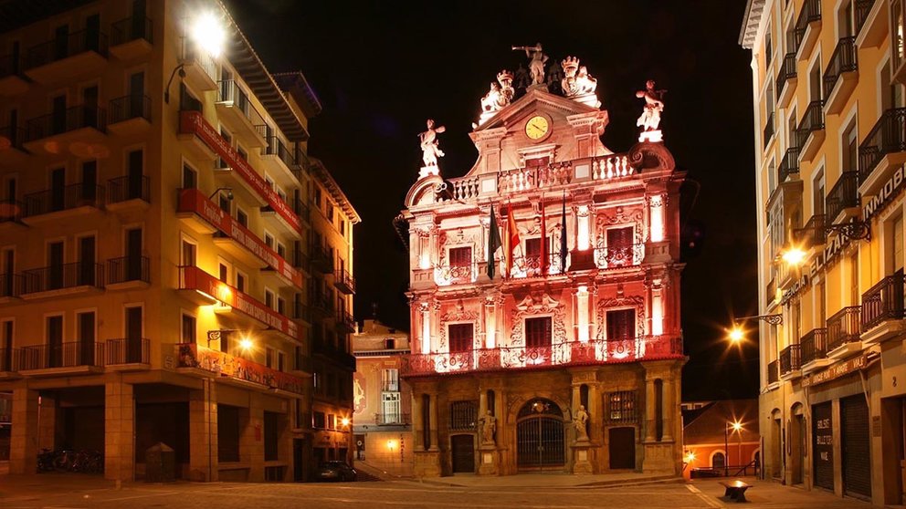 La fachada del Ayuntamiento de Pamplona iluminada de color rojo.