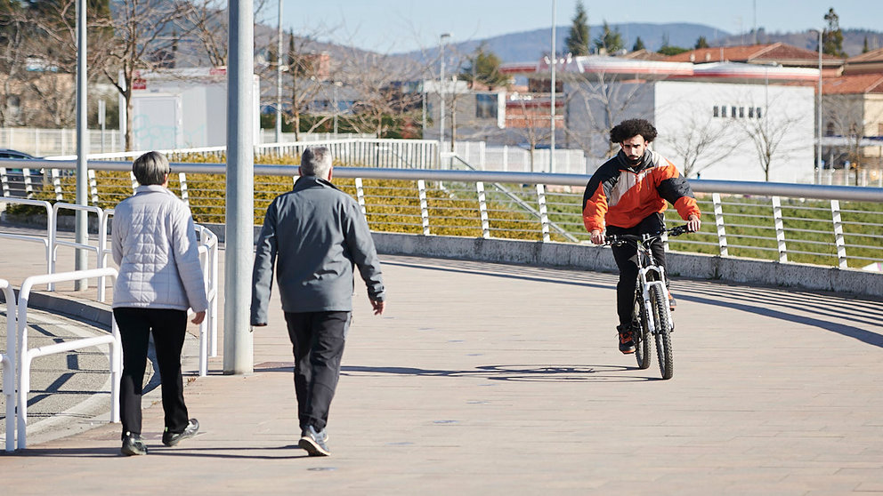 Un hombre monta en bici mientras una pareja pasea por Pamplona. PABLO LASAOSA
