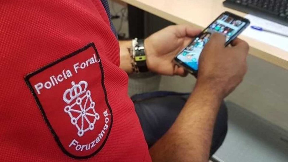Un agente de la Policía Foral revisa un teléfono móvil. 
POLICÍA FORAL / ARCHIVO