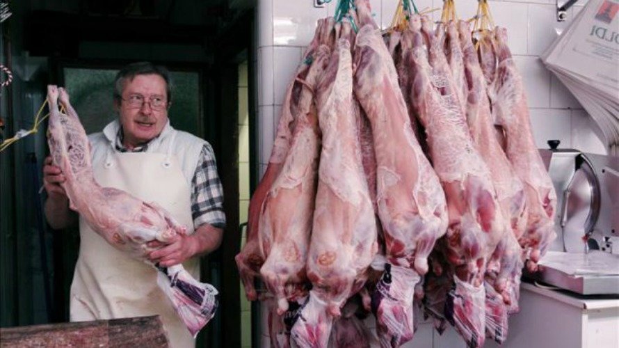 Un carnicero del mercado del Ensanche de Pamplona transporta un cordero para vender en su puesto. EFE.
