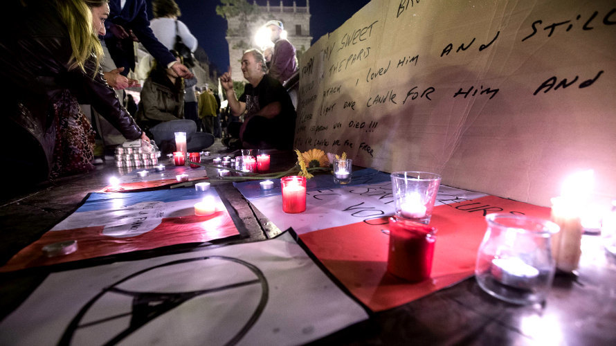 Varias personas colocan velas y flores por las víctimas de los atentados. EFE.