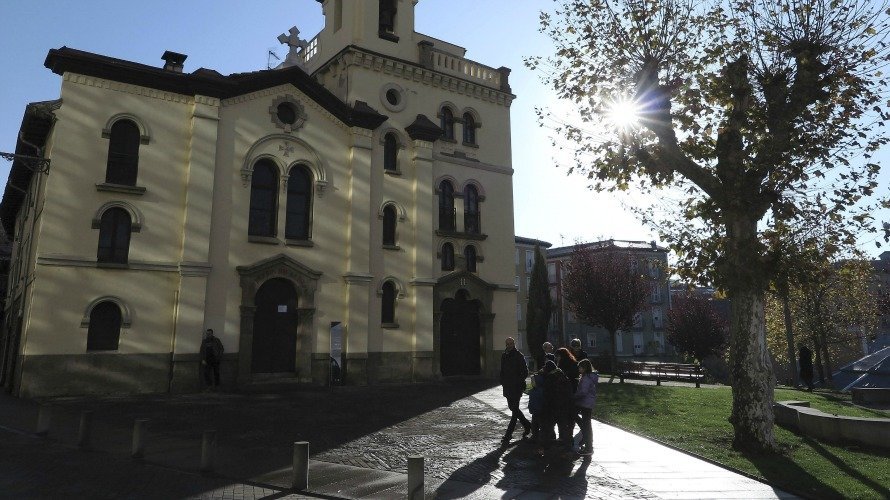 Tiempo, un grupo de personas pasea junto a la iglesia San Fermín de Aldapa. EFE.