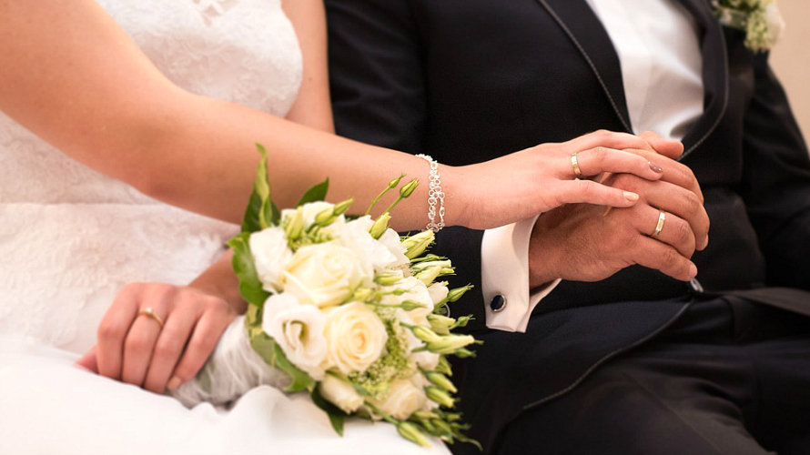 Una pareja se da la mano durante la boda.