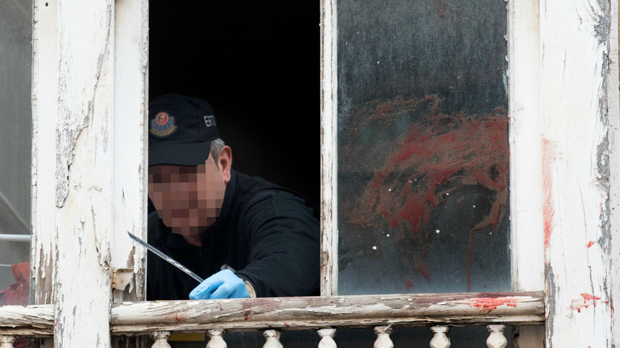 Un ertzaina toma pruebas en la ventana del domicilio del número 14 de la calle Libertad de Vitoria donde ocurrieron los hechos. EFE
