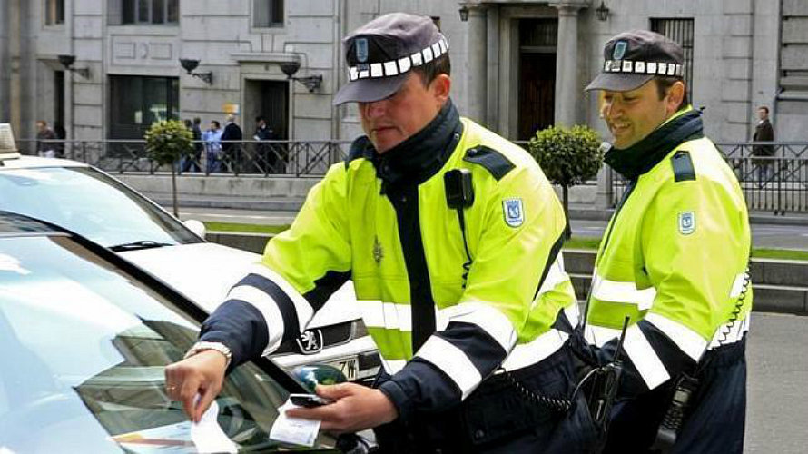Un agente de la Policía Municipal de Madrid deja el recibo de una multa en el. EFE