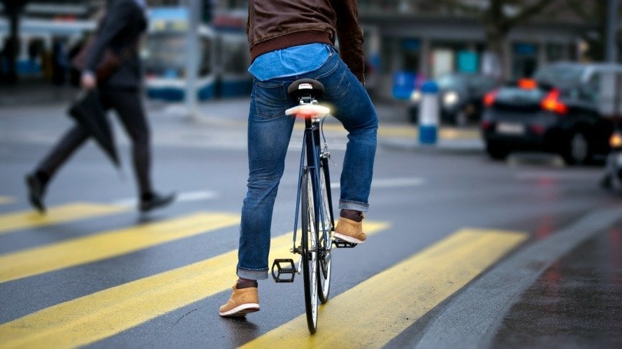 Un joven sobre una bicicleta, de espaldas.