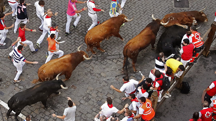 Dos toros de la ganadería de Jandilla caen a su paso por la curva de Telefónica durante el quinto encierro de los sanfermines 2016. EFE.Javier Lizón (2)