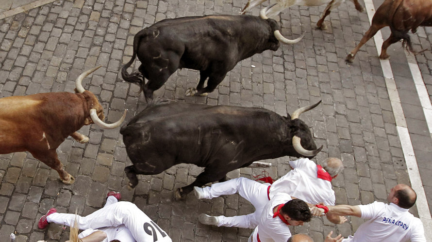 Un grupo de mozos caen ante tres toros de la ganadería extremeña de Jandilla en la entrada a la Plaza Consistorial de Pamplona. EFE.Villar López