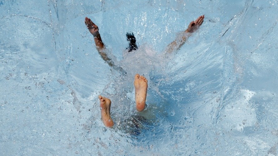 Una niña se zambulle en una piscina. Tiempo y calor. EFE