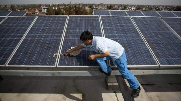 Un trabajador limpia una placa solar en la azotea de un edificio EFE