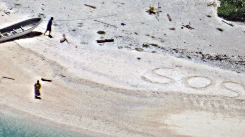 La pareja fue encontrada por escribir SOS (ayuda) en la playa