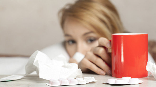 Una mujer enferma de gripe alcanza una taza para tomarse los medicamentos ARCHIVO