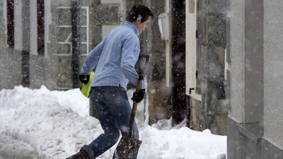 Una persona intenta entrar a su casa bajo una intensa nevada en Burguete (Navarra), comunidad donde continúa el temporal de nieve con esperoses que alcanzan los 50cm de nieve. EFE/Villar López