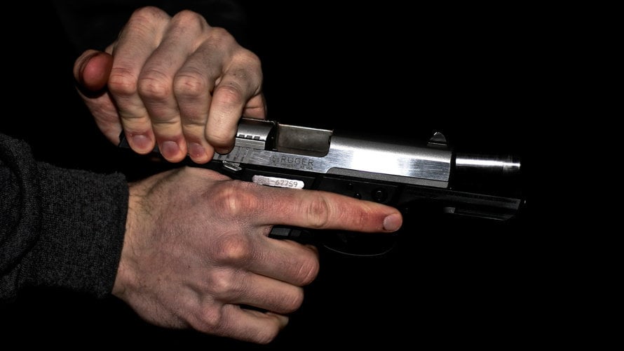 Un hombre prepara su pistola simulada para disparar. ARCHIVO