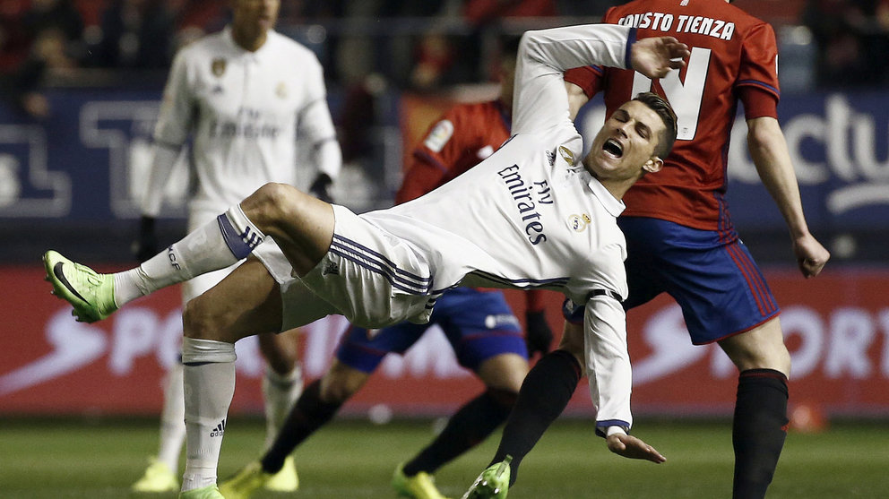 El delantero del Real Madrid Cristiano Ronaldo (i) cae ante Fausto Atienza, de Osasuna, durante el partido de Liga en Primera División disputado esta noche en el estadio de El Sadar, en Pamplona. EFE/Jesús Diges