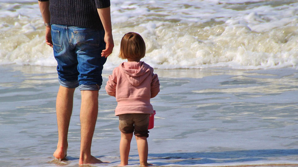 Un padre junto a su hija en la playa.