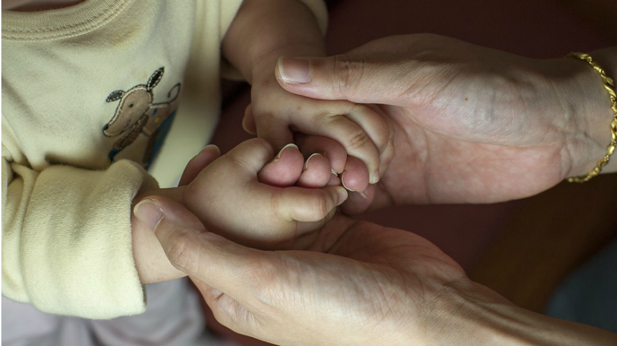 Una mujer agarra un bebé de las manos en una imagen de archivo. ARCHIVO