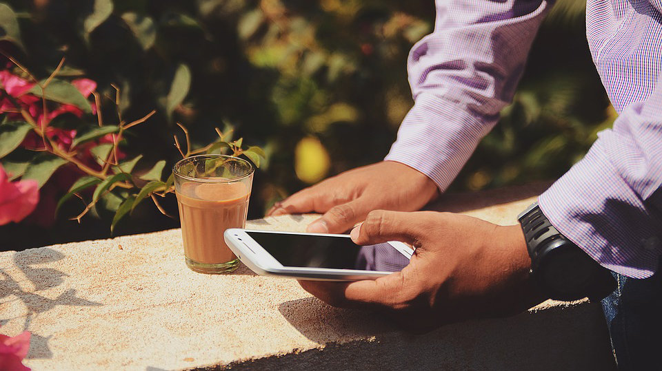 Imagen de un hombre manejando su smartphone mientras toma un café ARCHIVO