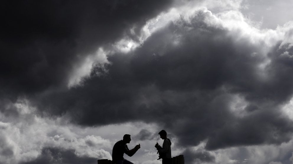 Dos personas juegan con un perro bajo un manto de nubes que cubren la comarca de Pamplona. EFE/J.D
