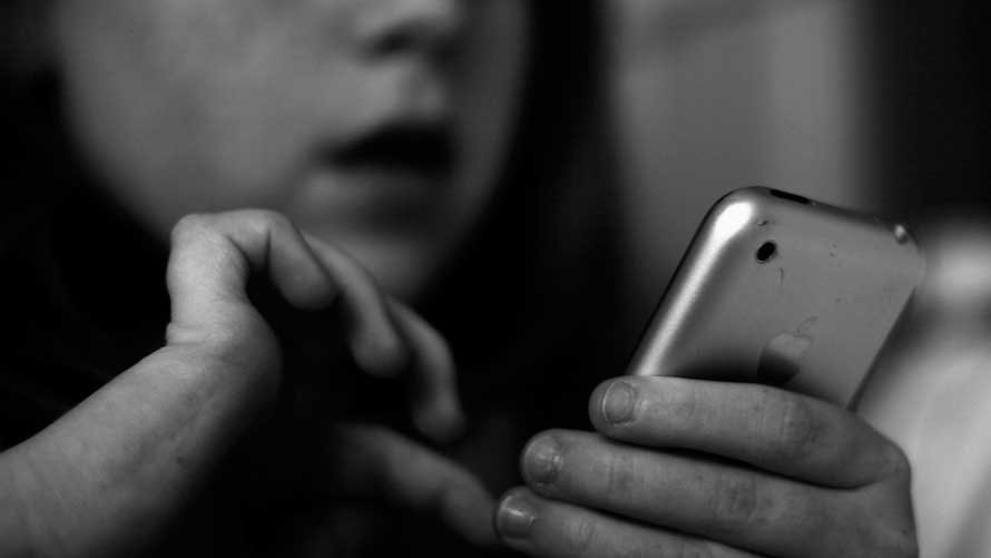 Una niña juega con un teléfono móvil. ARCHIVO