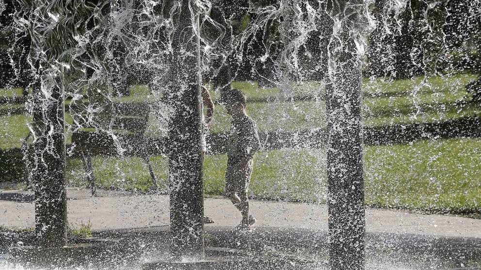 Un niño juega con el agua de una fuente de un parque de Pamplona en una jornada donde el calor ha sido protagonista en toda Navarra. EFE/Jesús Diges