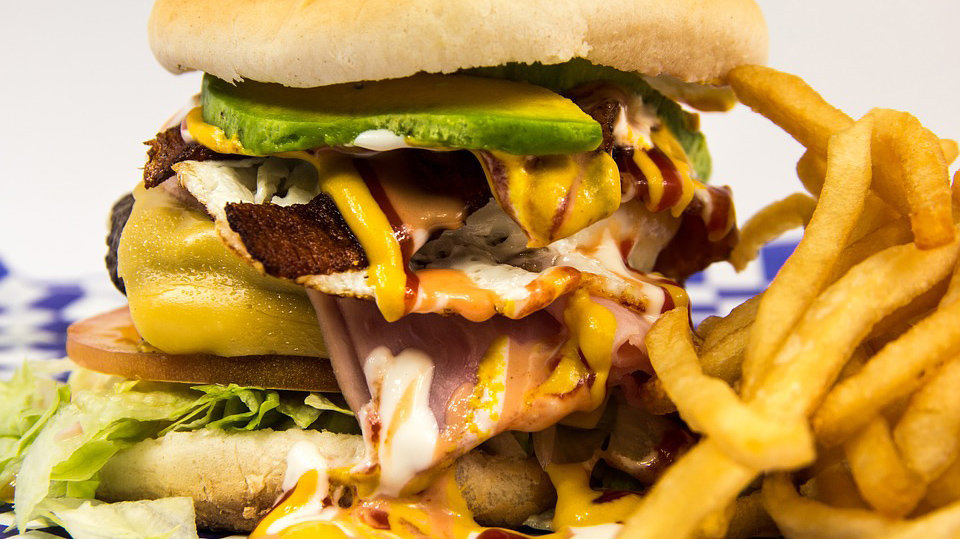 Una hamburguesa completa y patatas fritas, alimentos ricos en colesterol.